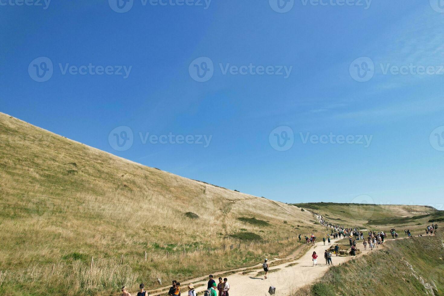 High Angle View of People are Approaching to Durdle Door Beach Which is Most Famous Tourist Attraction Place Through Walking Distance over Landscape and Hills. Captured on September 9th, 2023 photo