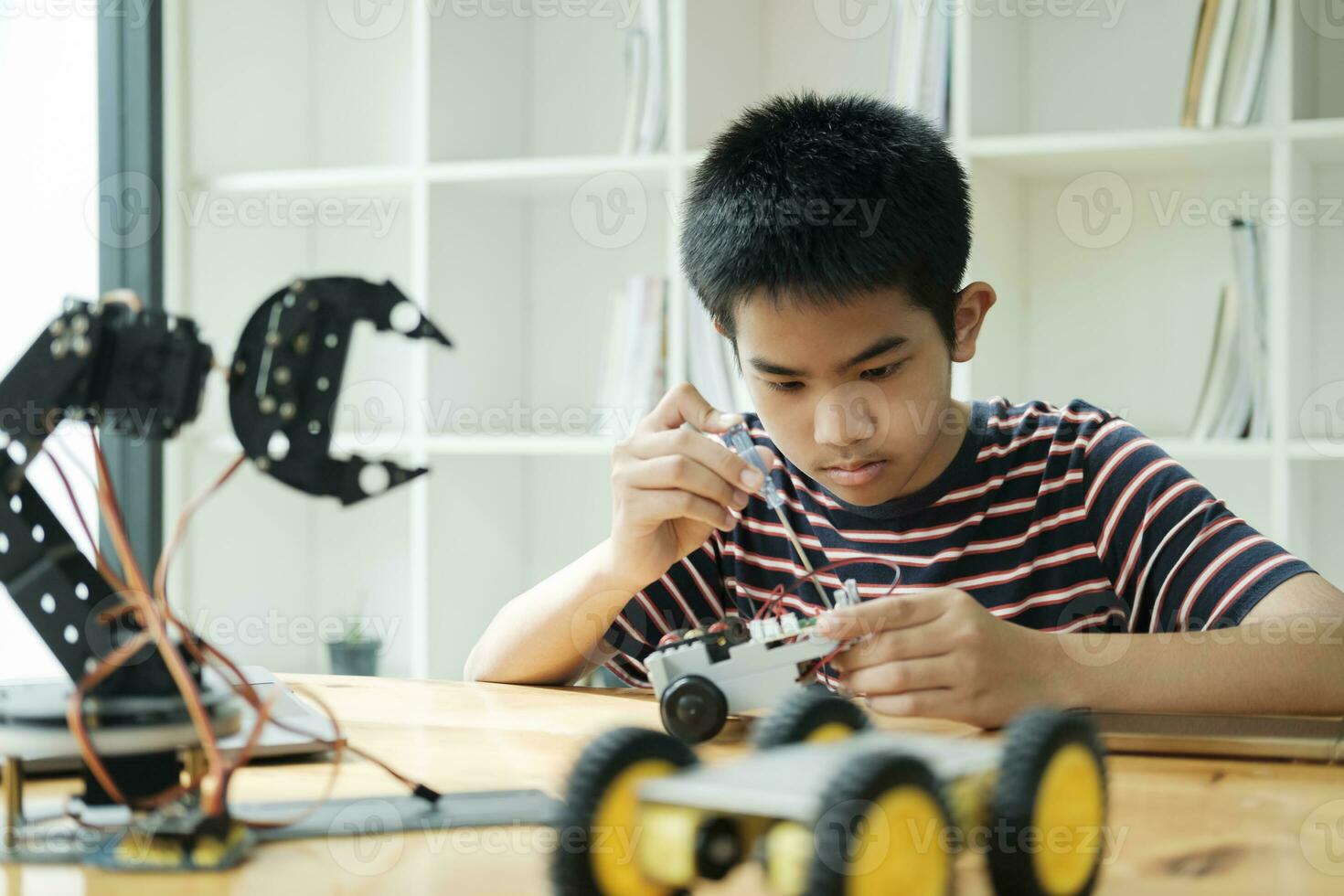 Asian teenager doing robot project in science classroom. technology of robotics programing and STEM education concept. photo