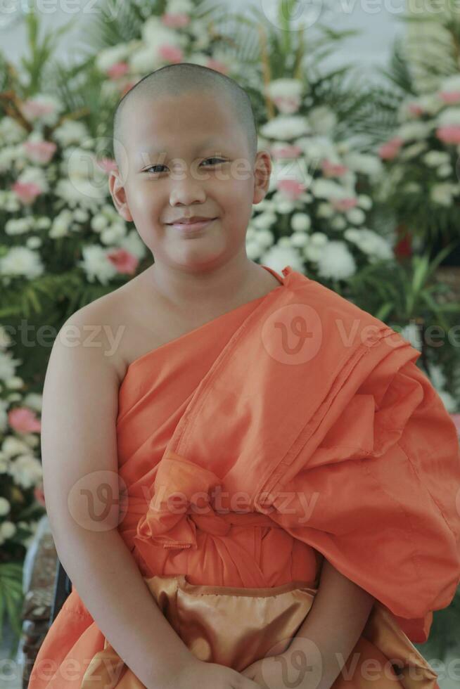 portrait of buddhist novice wearing thai monk clothes standing outdoor photo
