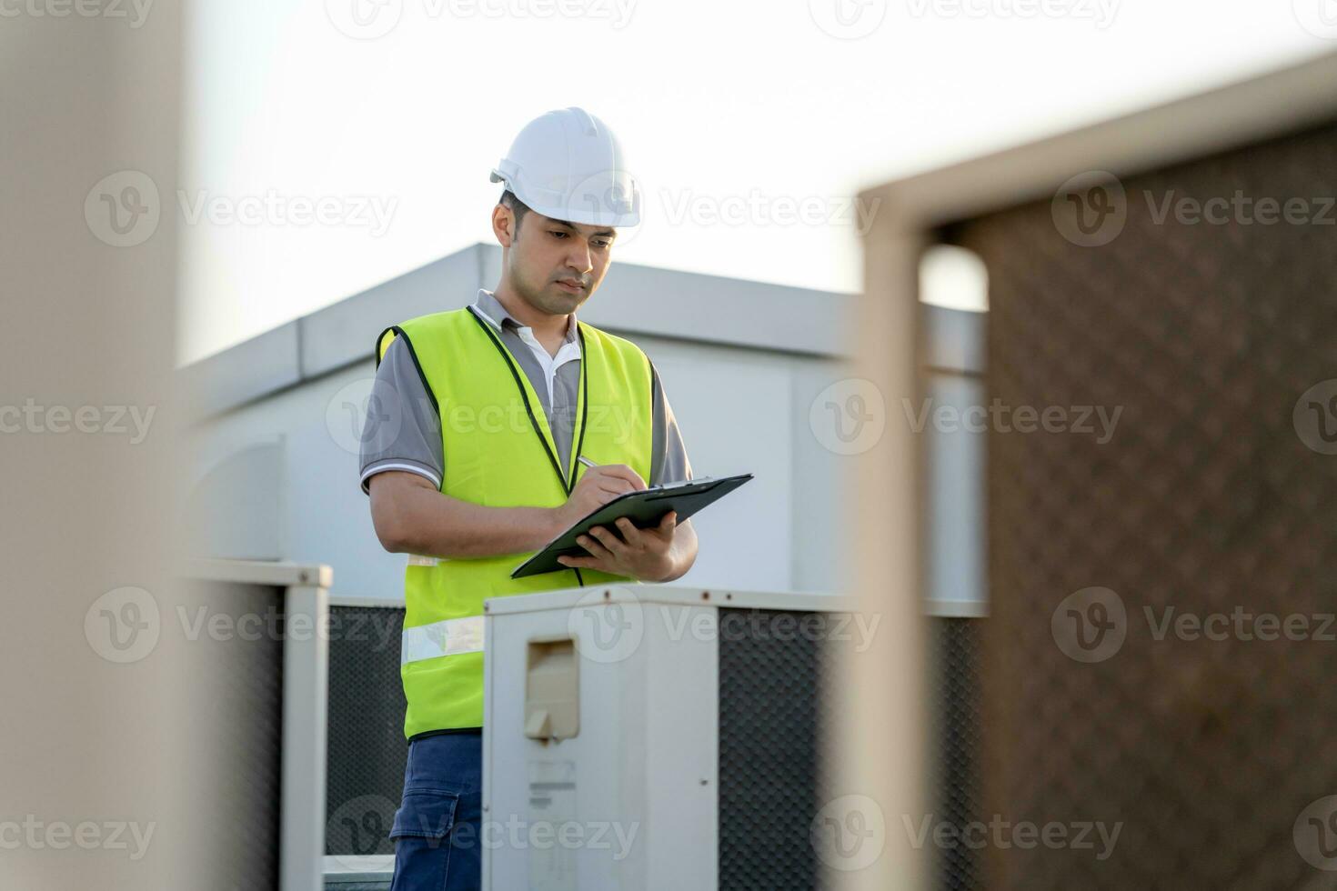 Asian maintenance engineer works on the roof of factory. contractor inspect compressor system and plans installation of air condition systems in construction. Checklist, inspector, control photo