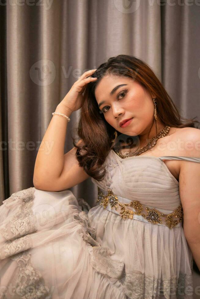 an Asian woman is sitting pretty while wearing a party dress and makeup on her face while waiting for her boyfriend at a party photo