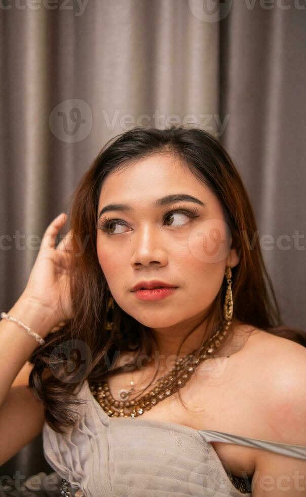 an Asian woman is sitting pretty while wearing a party dress and makeup on her face while waiting for her boyfriend at a party photo