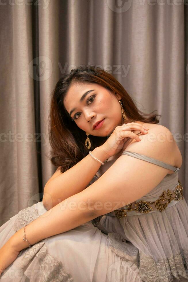 an Asian woman is sitting pretty while wearing a party dress and makeup on her face while waiting for her boyfriend at a party photo