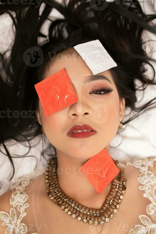 un asiático mujer con un oro collar caídas dormido con un condón envoltura en su cara en un hotel foto