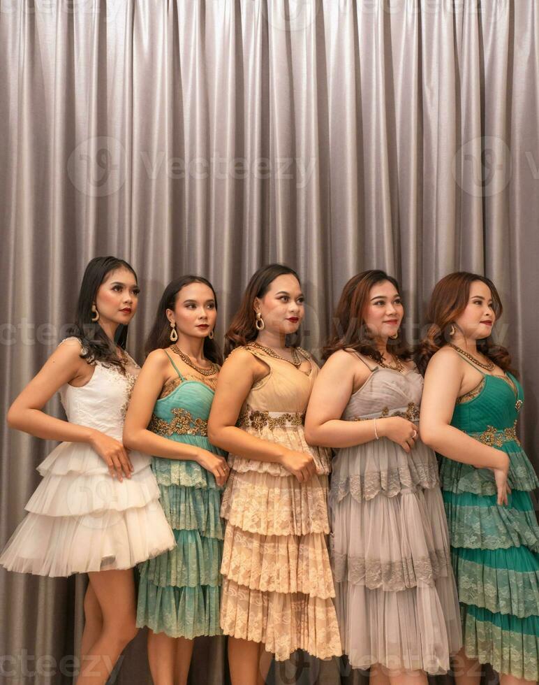 a group of Asian women are standing in front of the curtains of a luxury hotel while wearing dresses at a party photo
