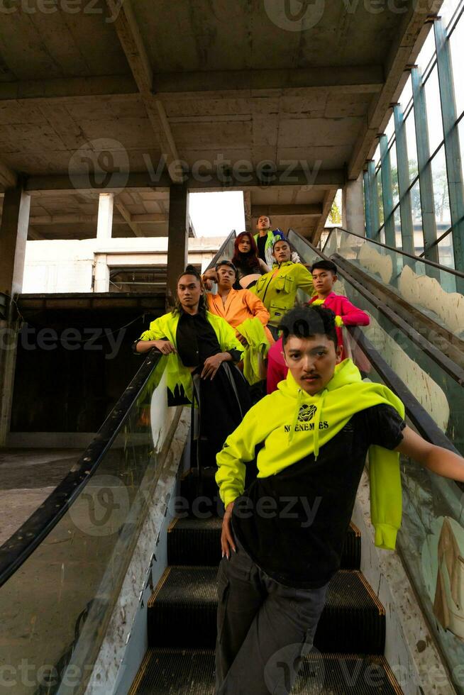 a group of Asian men in lemon green jackets are standing with their friends on the escalator photo
