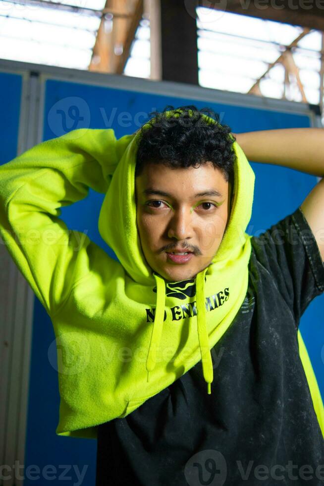 an Asian man with black curly hair posing in a green hoodie photo