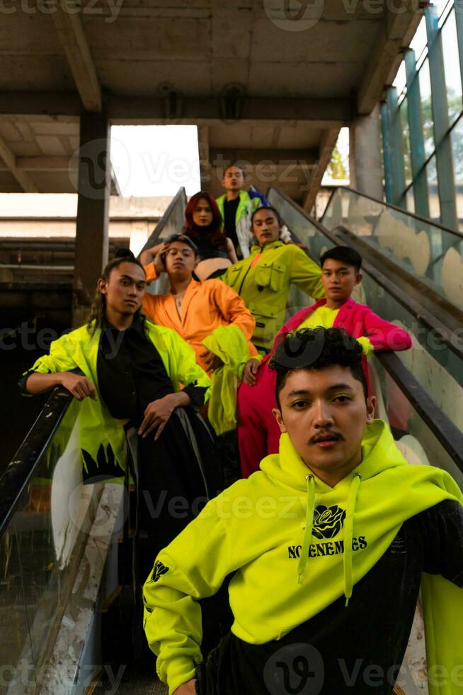 a group of Asian men in lemon green jackets are standing with their friends on the escalator photo