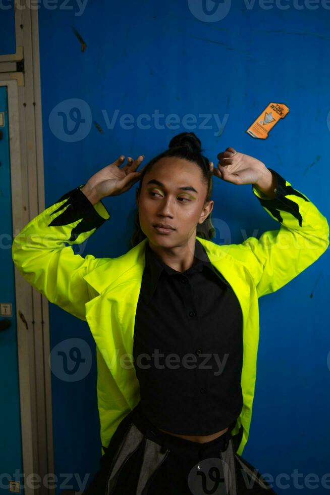 an Asian man in a green jacket posing in front of a blue locker photo