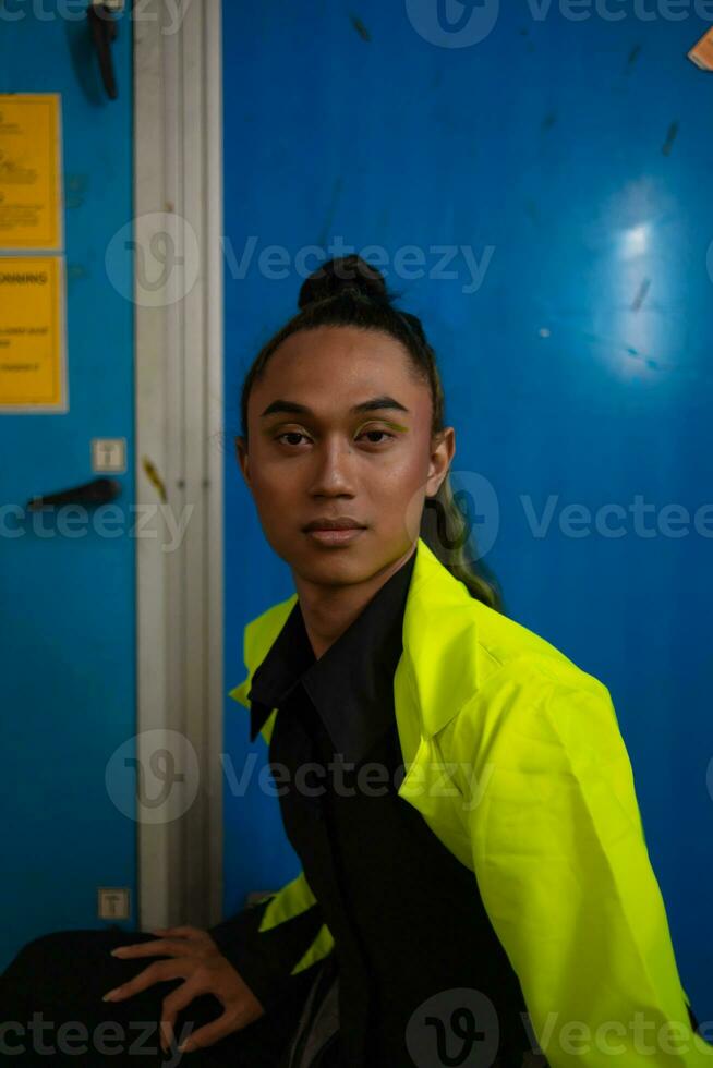 an Asian man with exotic skin squats in front of a blue background photo