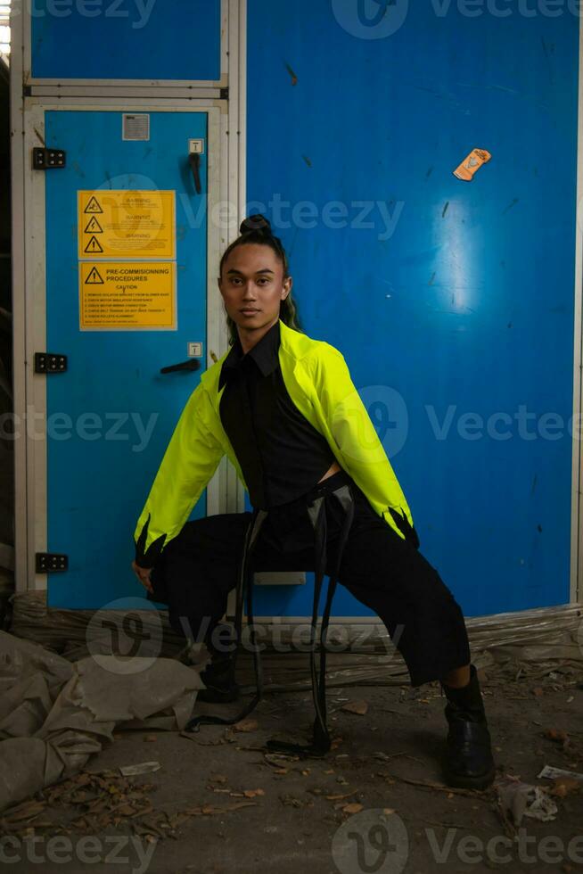 an Asian man with exotic skin squats in front of a blue background photo