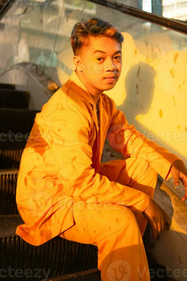 an Asian man in a yellow suit is sitting on a lift in a building photo