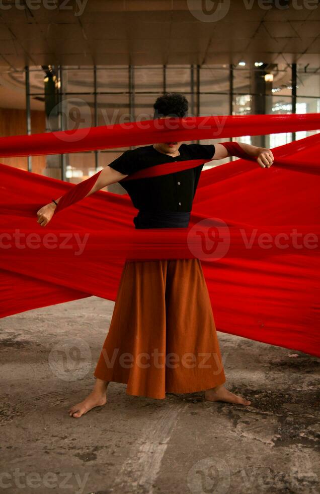 un asiático hombre en pie con orgullo entre el rojo paño ese cuelga en un antiguo edificio foto