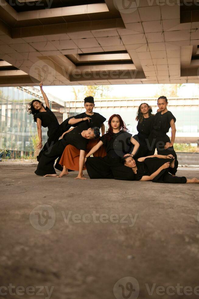 a group of Asian men posing cheerfully with their friends while wearing black photo