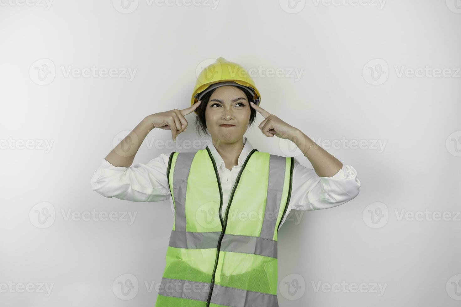 A thoughtful young woman labor worker wearing safety helmet and vest is looking aside to an idea on copy space , isolated by white background. Labor's day concept. photo