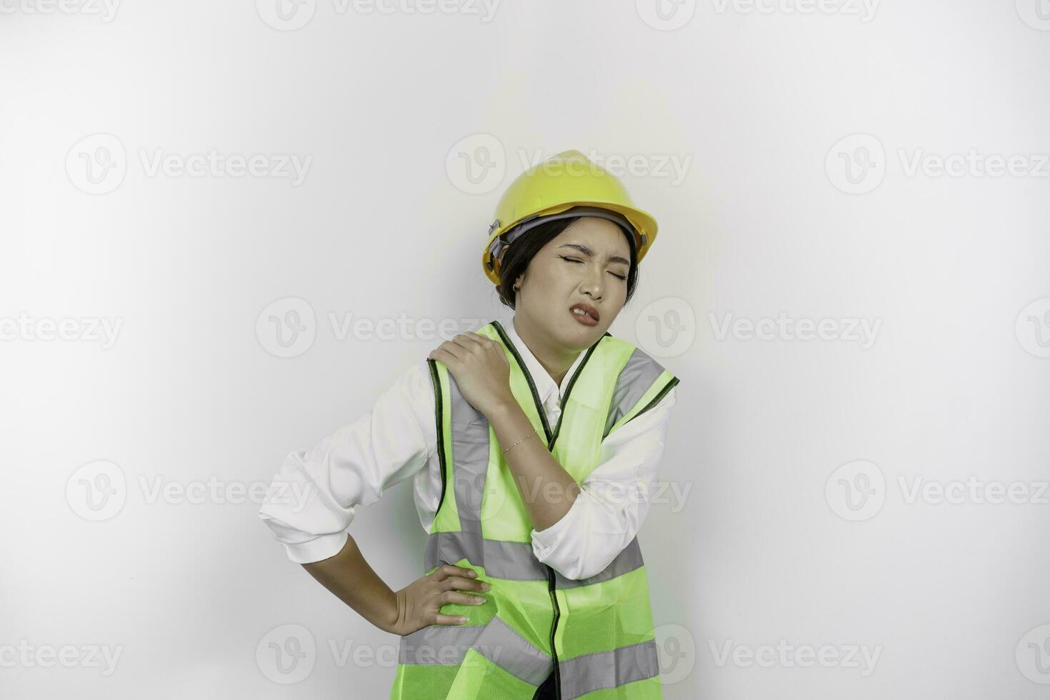 cansado asiático mujer labor trabajador vistiendo un la seguridad casco y chaleco sufrimiento desde dolor, músculo espasmo aislado blanco antecedentes. mano de obra día concepto. foto