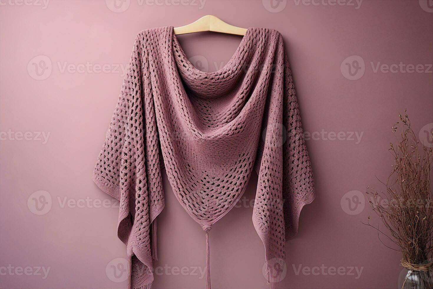 A mauve crocheted shawl, made of a soft, lightweight fabric, draped elegantly over a hanger. Soft fabric texture, neutral background, warmth and coziness concept. AI Generated. photo