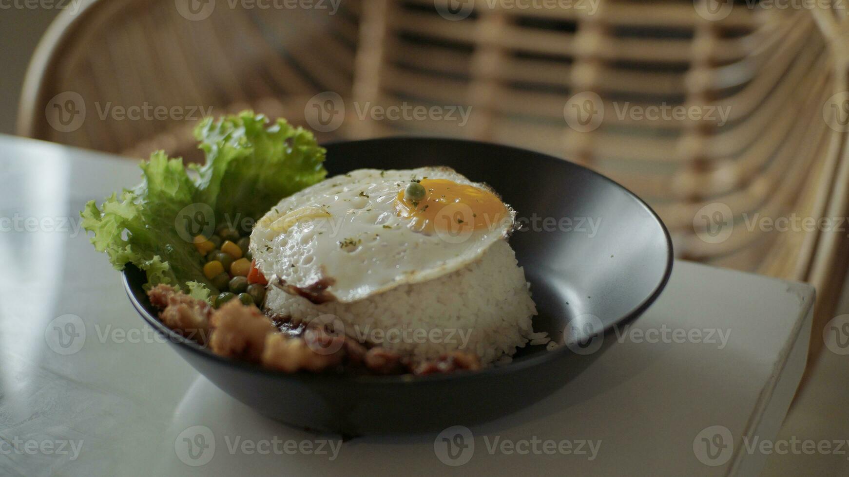 Rice bowl with sunny side up egg, chicken, vegetables and lettuce on white table. Traditional and modern restaurant concept. photo
