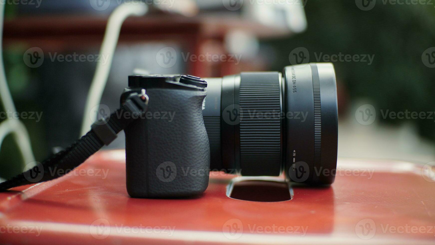 Close-up of a digital camera placed on a table after being used by a photographer. A mirrorless camera that is very compact and easy to carry when traveling. photo