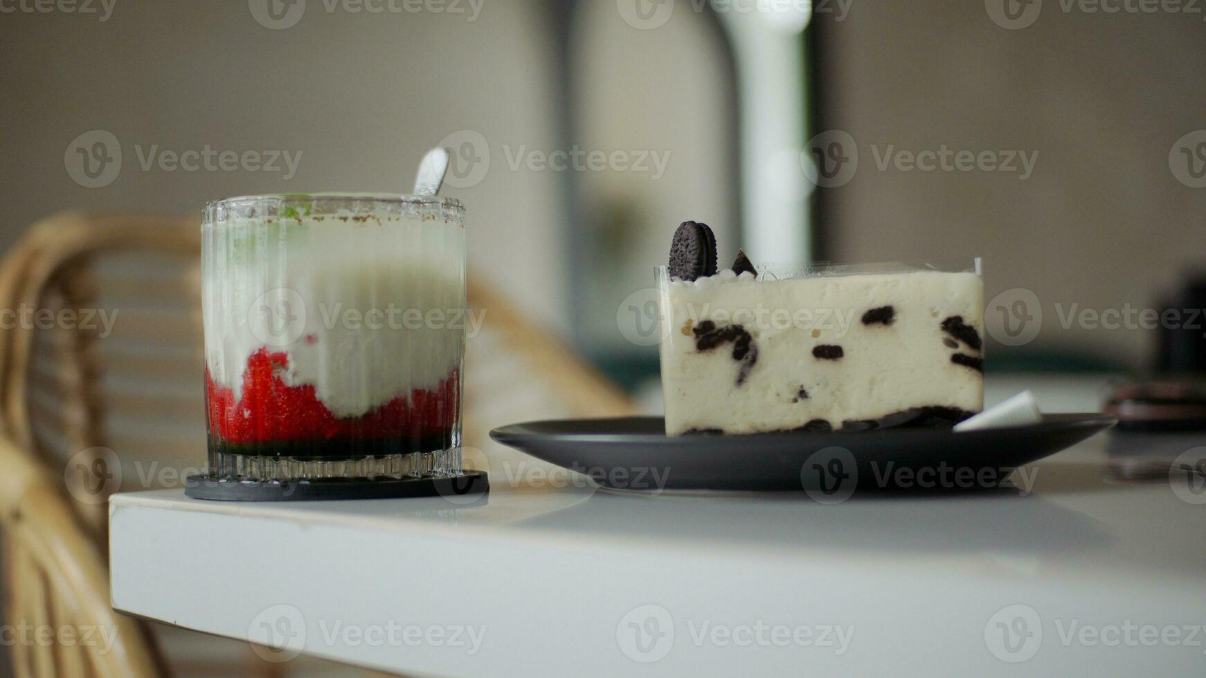 A glass of strawberry drink and chocolate cheesecake on white table in cafe. photo