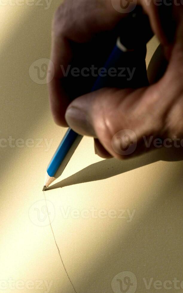 Human's hand holding pencil to write on the paper in shadow photo