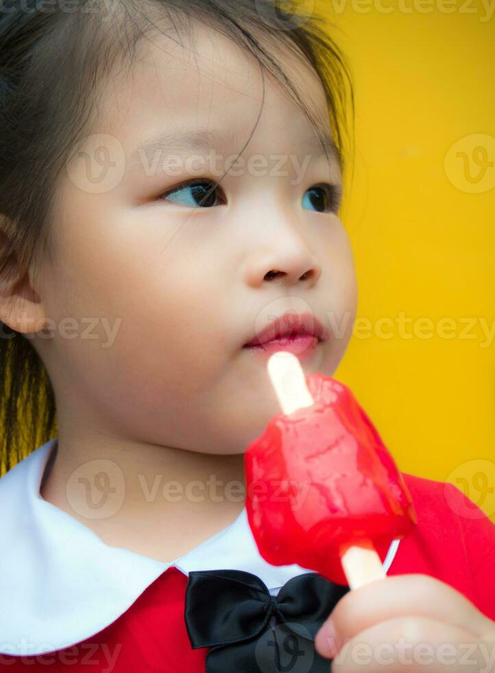 Little girls in red student dressed Eating a red popsicle photo