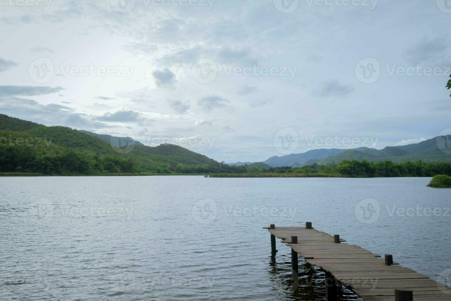 Outdoor wood bridge and nature water lake with blue sky, relaxation calm pier horizon reflection sun cloud scenic vacation, silence morning in countryside with mountain sunrise scenery, evening river photo