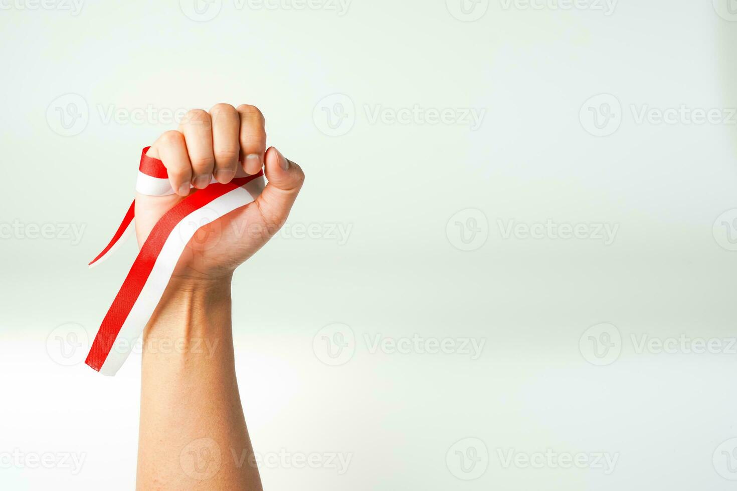 hand holding ribbon red white flag of Indonesia independence day August 17th  isolated on white background photo