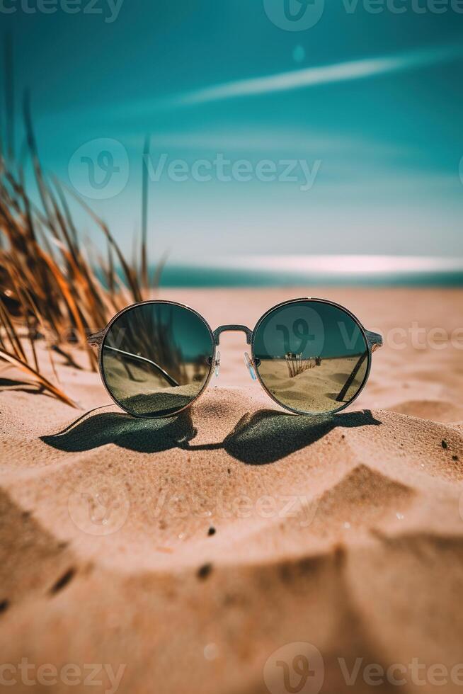 a pair of sunglasses sitting on top of a sandy beach photo