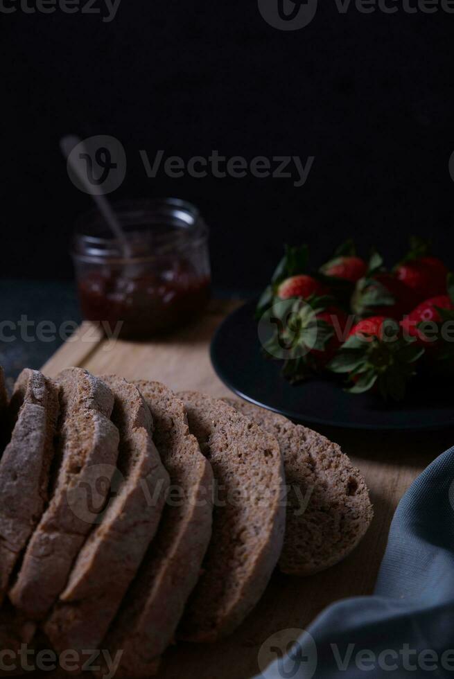 Freshly prepared and sliced bread served on the table with jam and strawberries. photo
