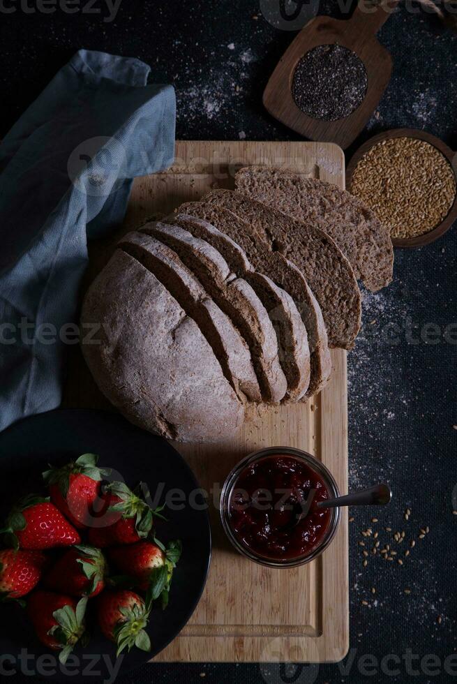 Freshly prepared and sliced bread served on the table with jam and strawberries. photo