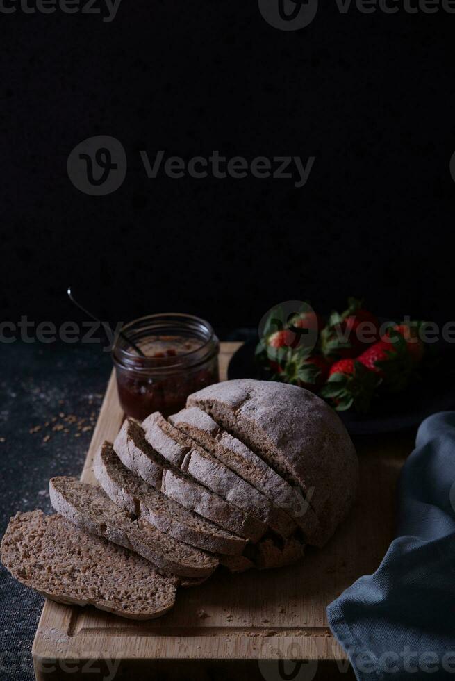 Freshly prepared and sliced bread served on the table with jam and strawberries. photo