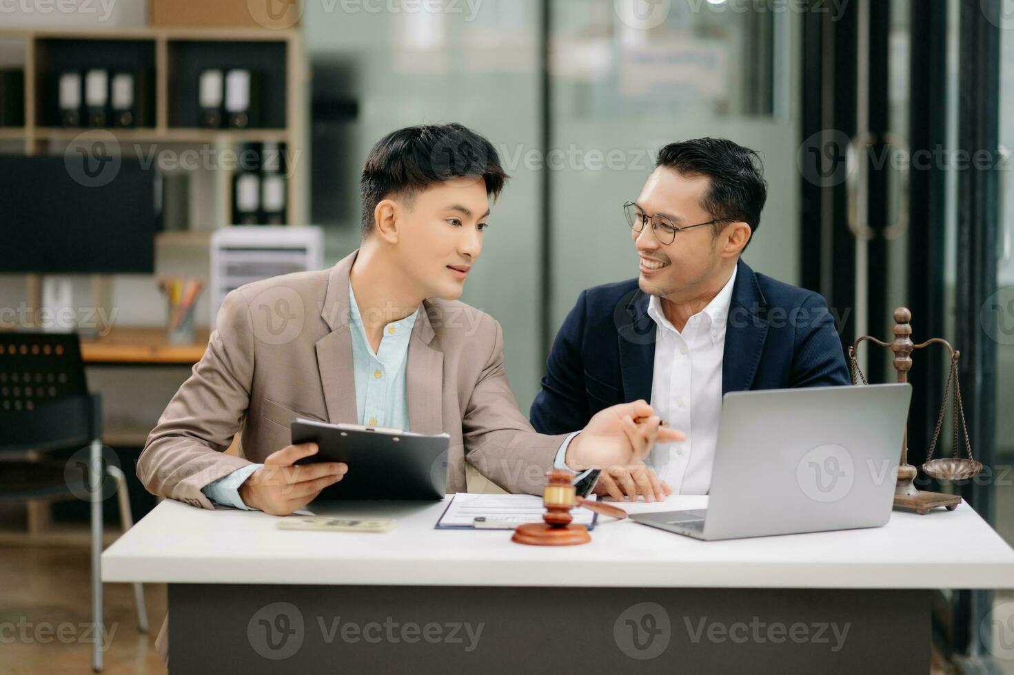 Two lawyers are discussing about contract paper, law matters determination, pointing.law and hammer on the table photo