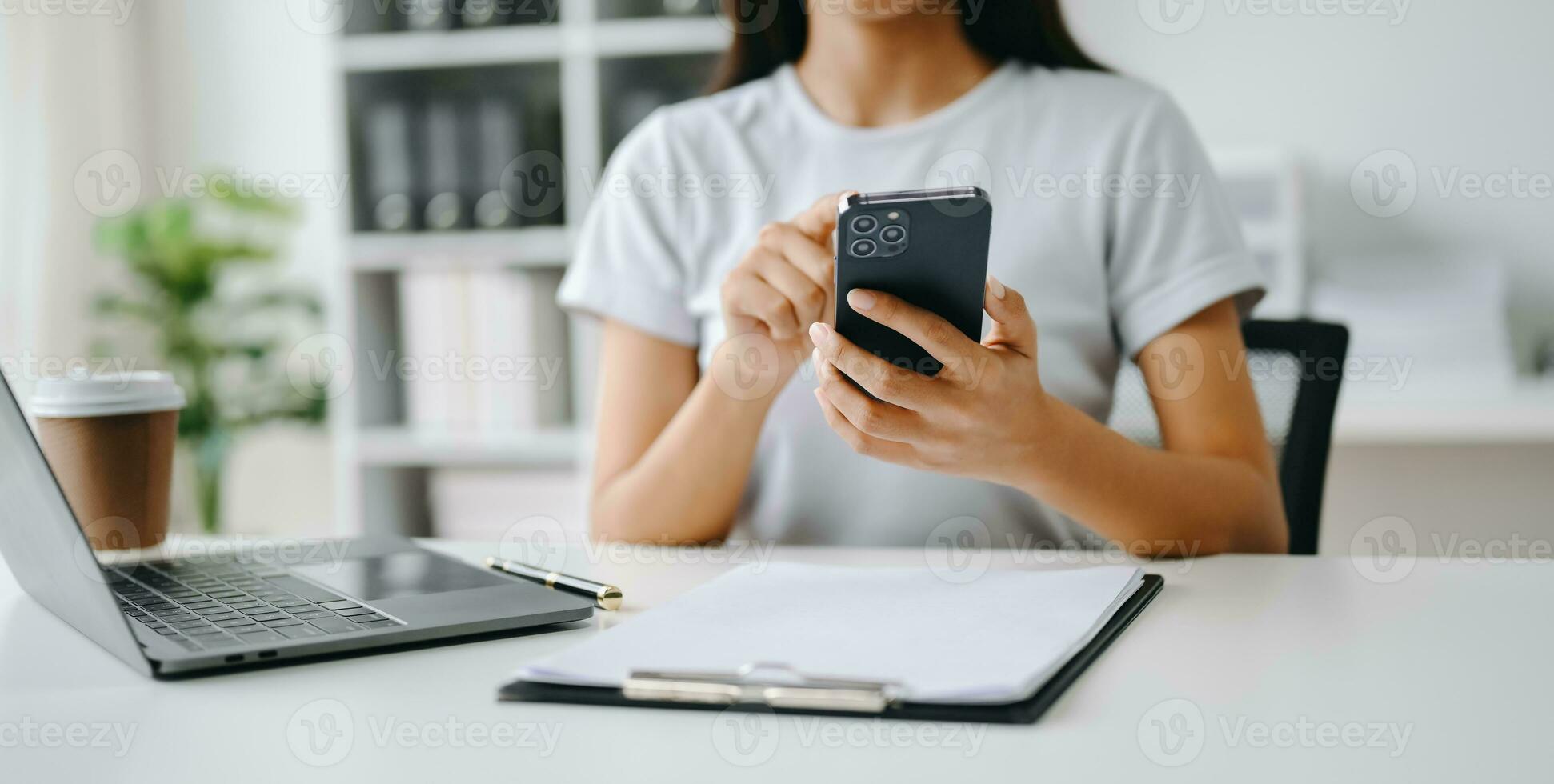 Asian Woman using smart phone for mobile payments online shopping, omni channel, sitting on table, virtual icons graphics interface screen photo