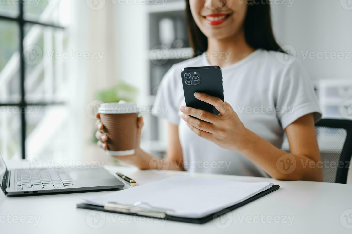 Asian Woman using smart phone for mobile payments online shopping, omni channel, sitting on table, virtual icons graphics interface screen photo