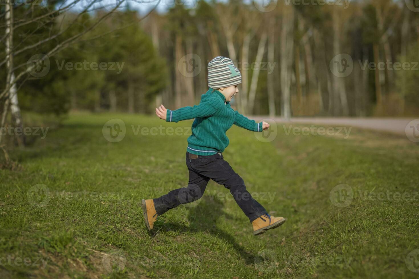 gracioso chico camina en el primavera parque, carreras, saltos y disfruta foto