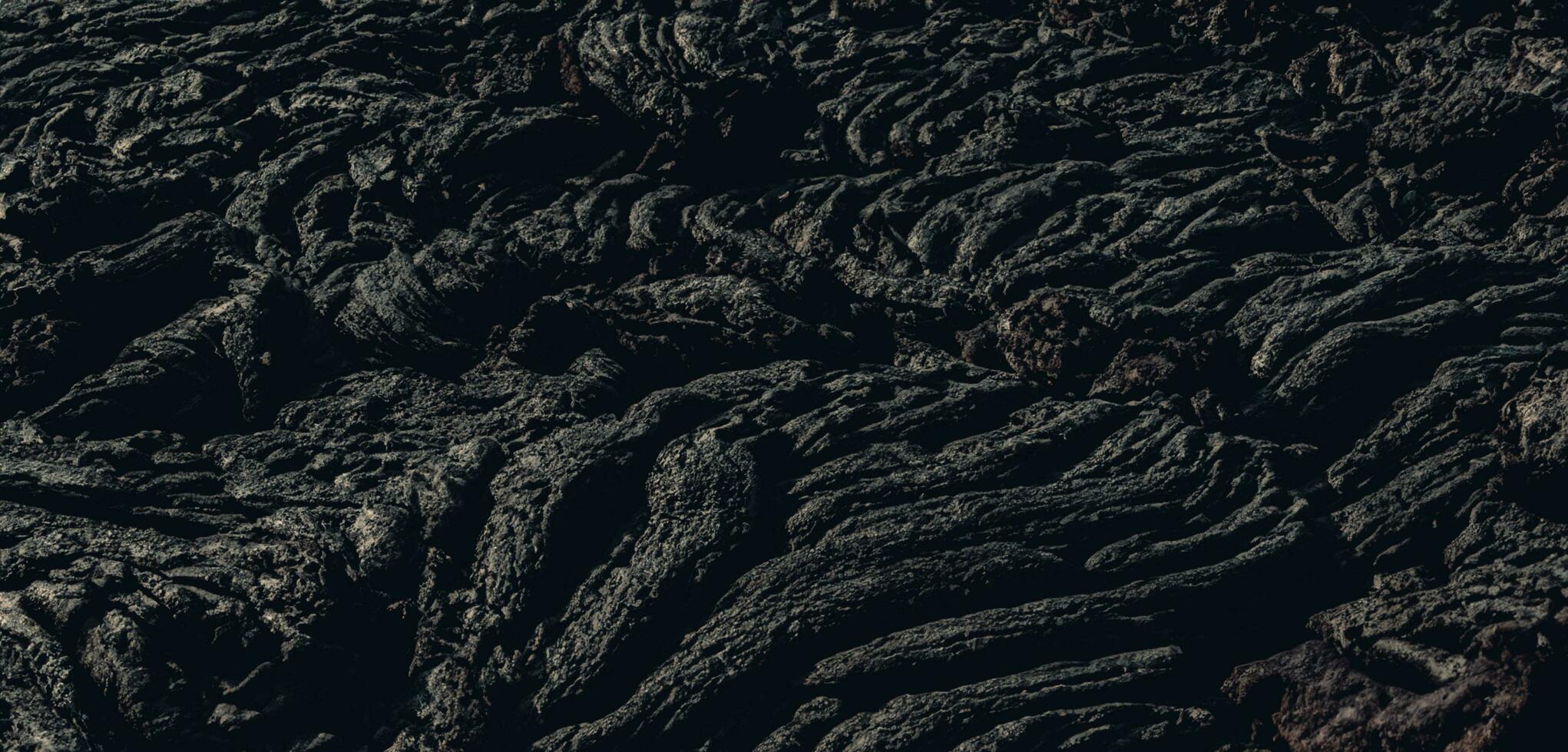 The lava surface cools and hardens into rock Clumps of dark black lava photo