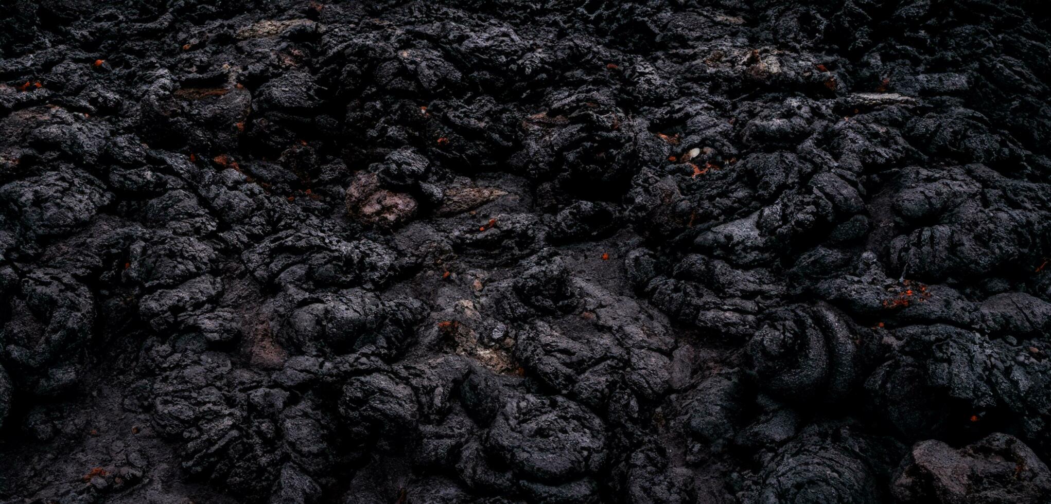 The lava surface cools and hardens into rock Clumps of dark black lava photo