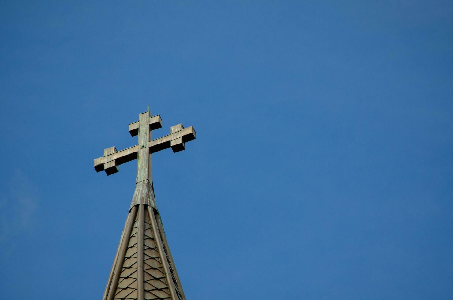cruzar en pie en un Iglesia techo ,geométrico figura consistente de dos intersectando líneas o barras en contra el azul cielo. foto