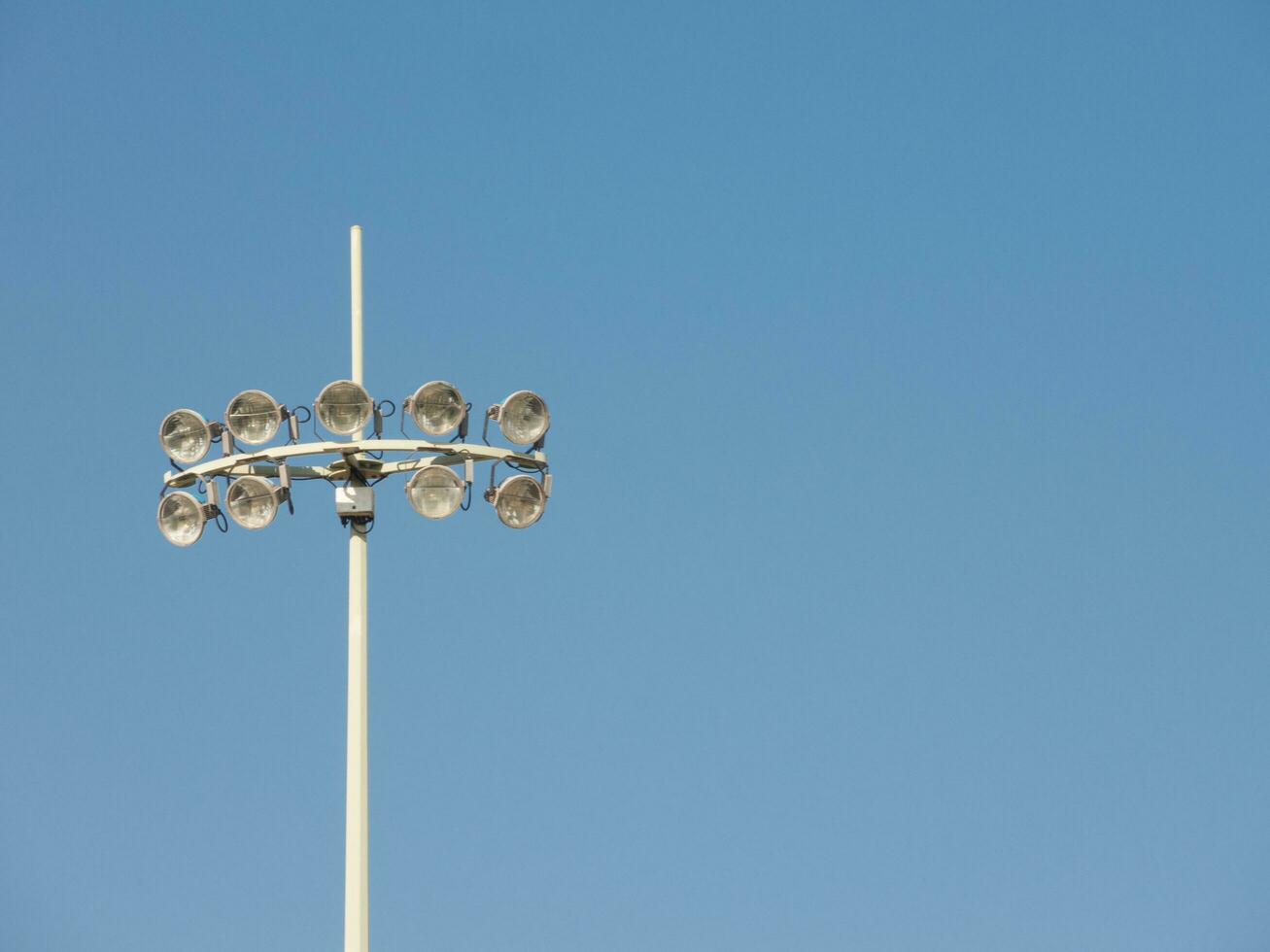 deporte estadio con diez luces en pie en contra azul cielo día, Luz de inundación es un de haz amplio, Alta intensidad artificial luz, al aire libre jugando campos mientras un al aire libre Deportes evento . foto