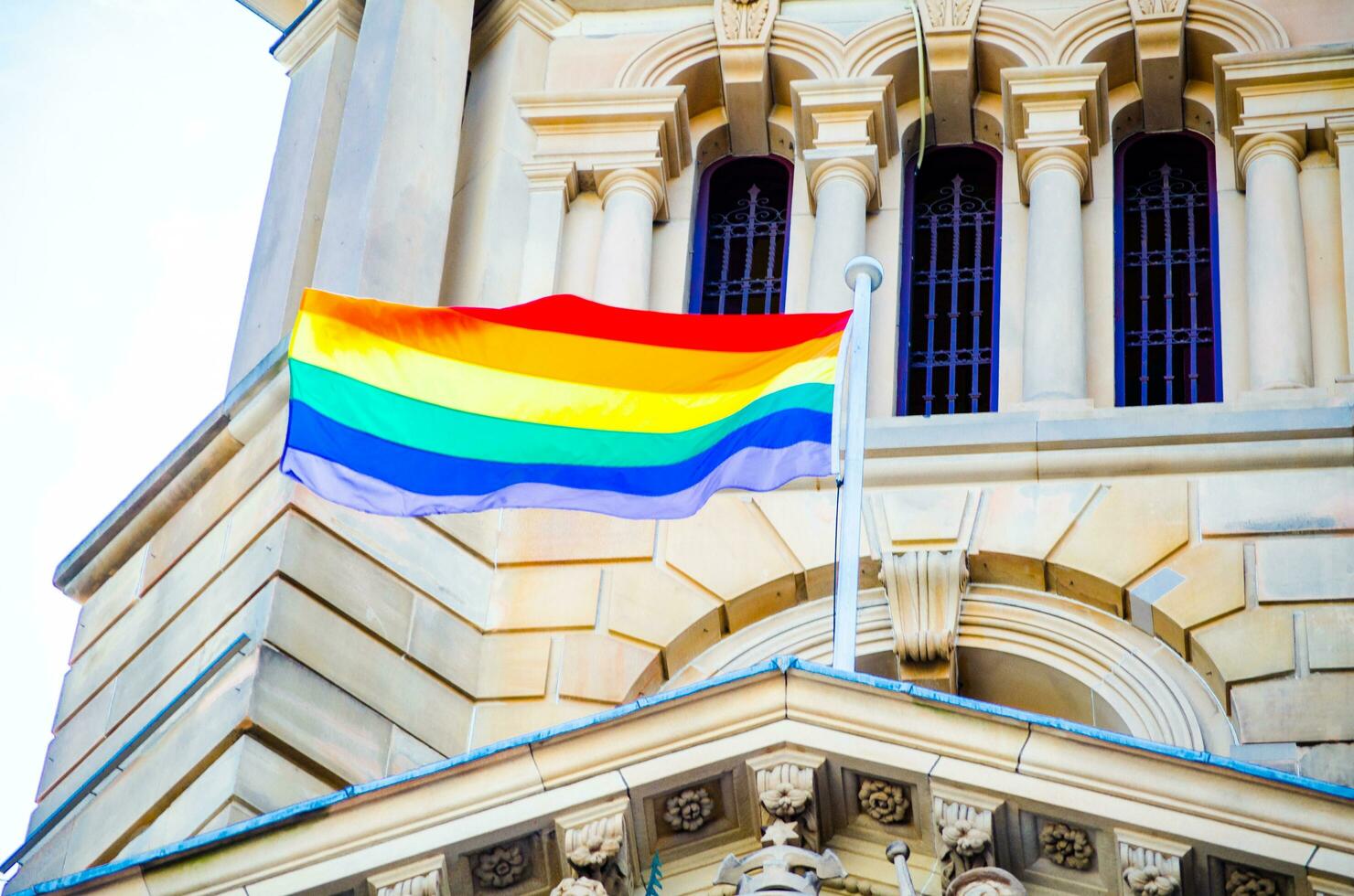 el arco iris bandera tiene volado en fachada edificio en pueblo salón Australia, es un símbolo de lgbt orgullo y lgbt social movimientos foto