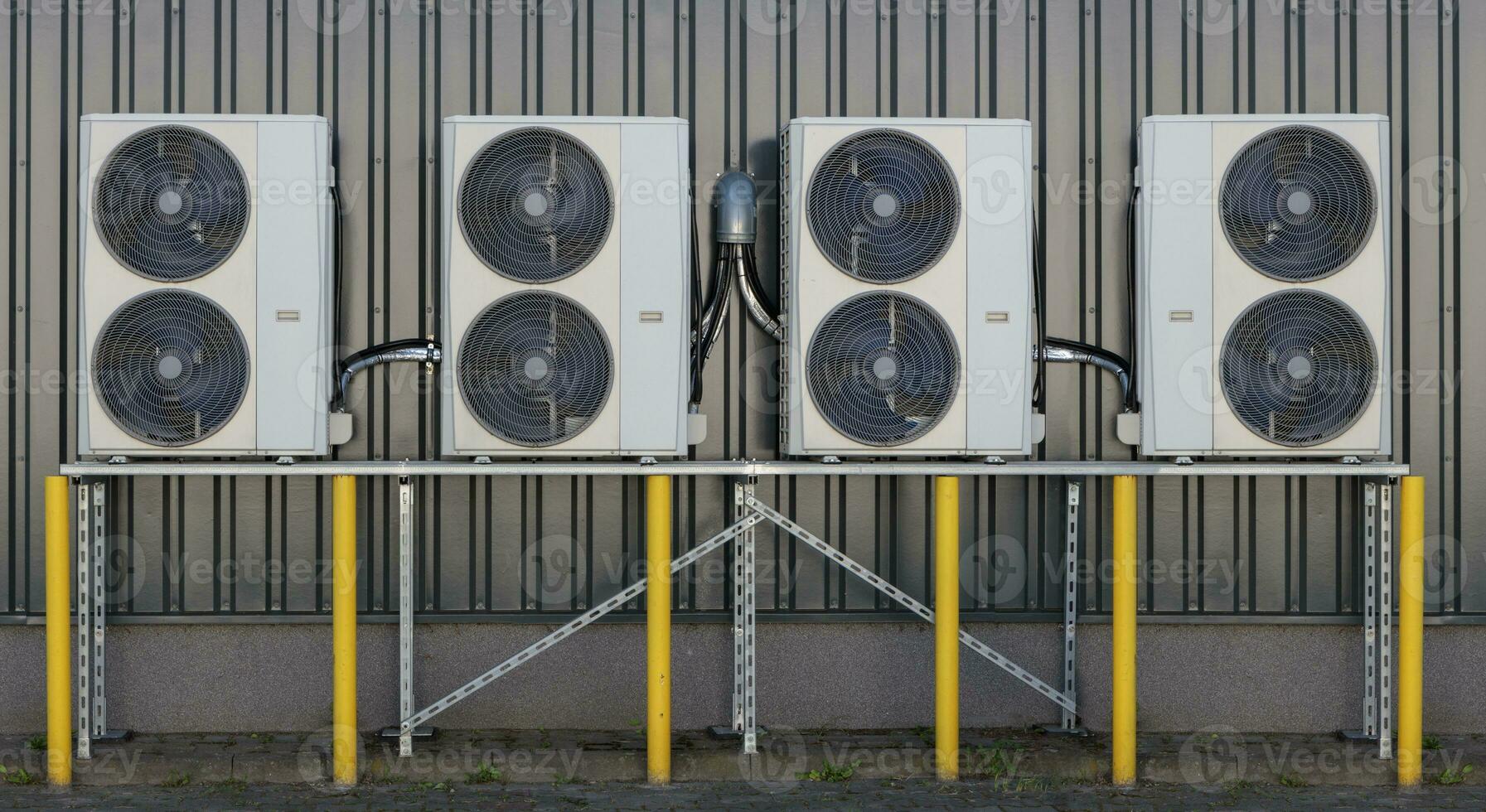 A series of split air conditioner condensers mounted on a building wall, showcasing modern cooling technology. photo