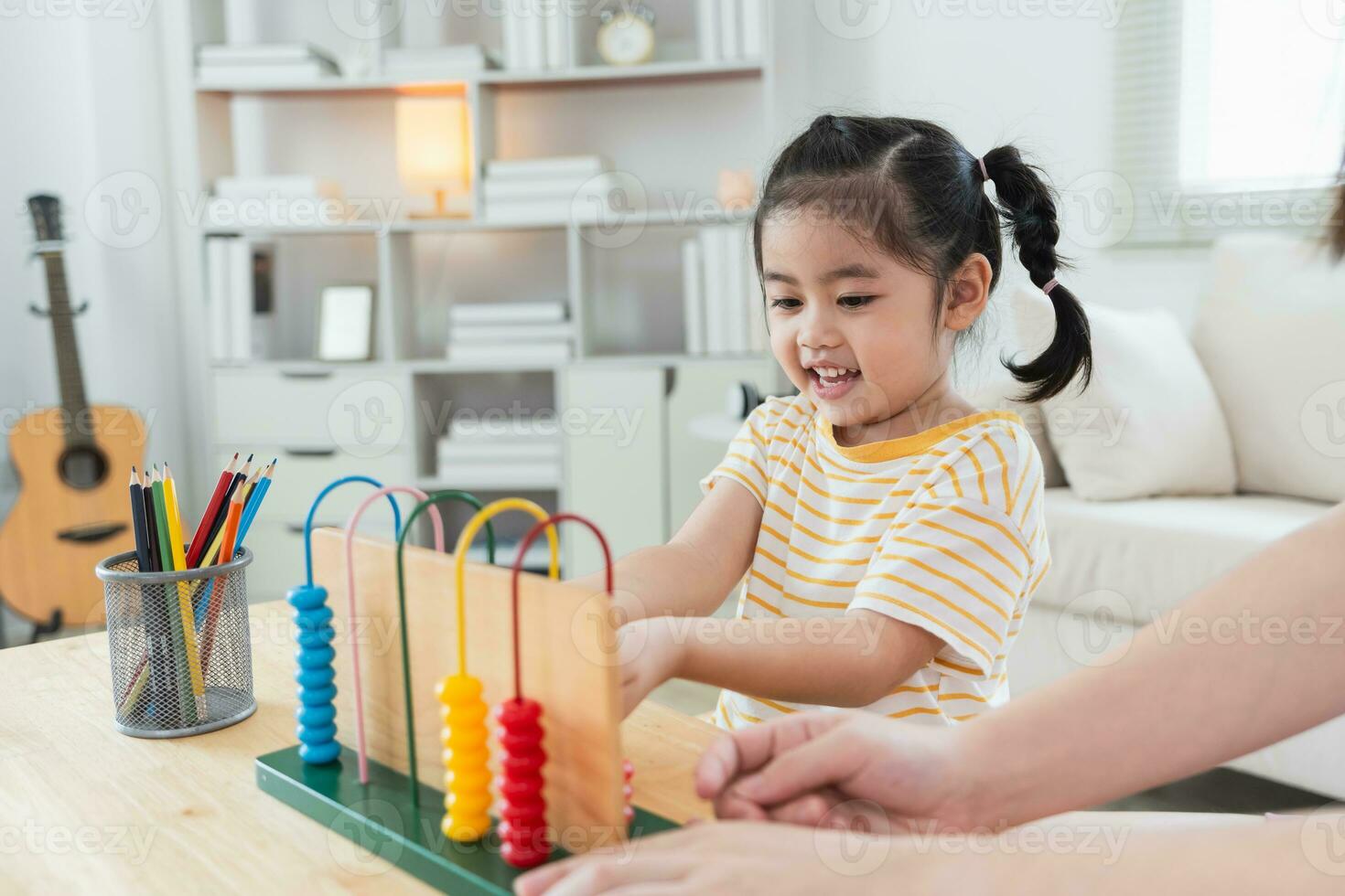Young cute Asian girl and her parent mother mom is learning the abacus with colored beads to learn how to count sofa in the living room at home. Child baby girl development studing concept. photo