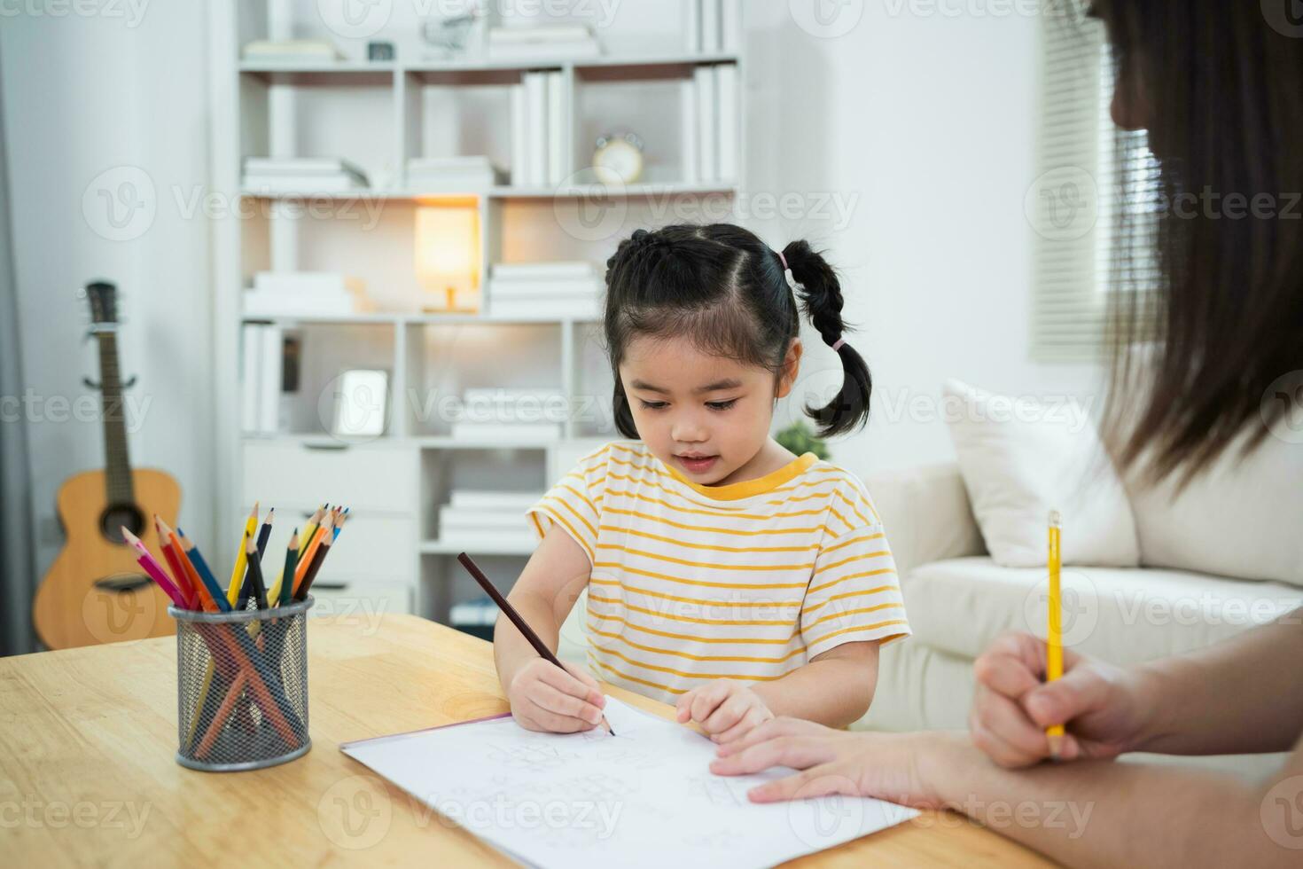 Cute little child painting with colorful paints. Asian girl and mother using crayon drawing color. Daughter and mom doing homework coloring cartoon characters. Baby artist activity lifestyle concept. photo