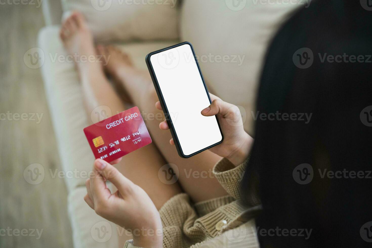 Woman using mobile phone smartphone holding credit card to shopping online. asian woman shopping on sofa couch in living room at home. Online shopping, e-commerce, internet banking, spending money. photo