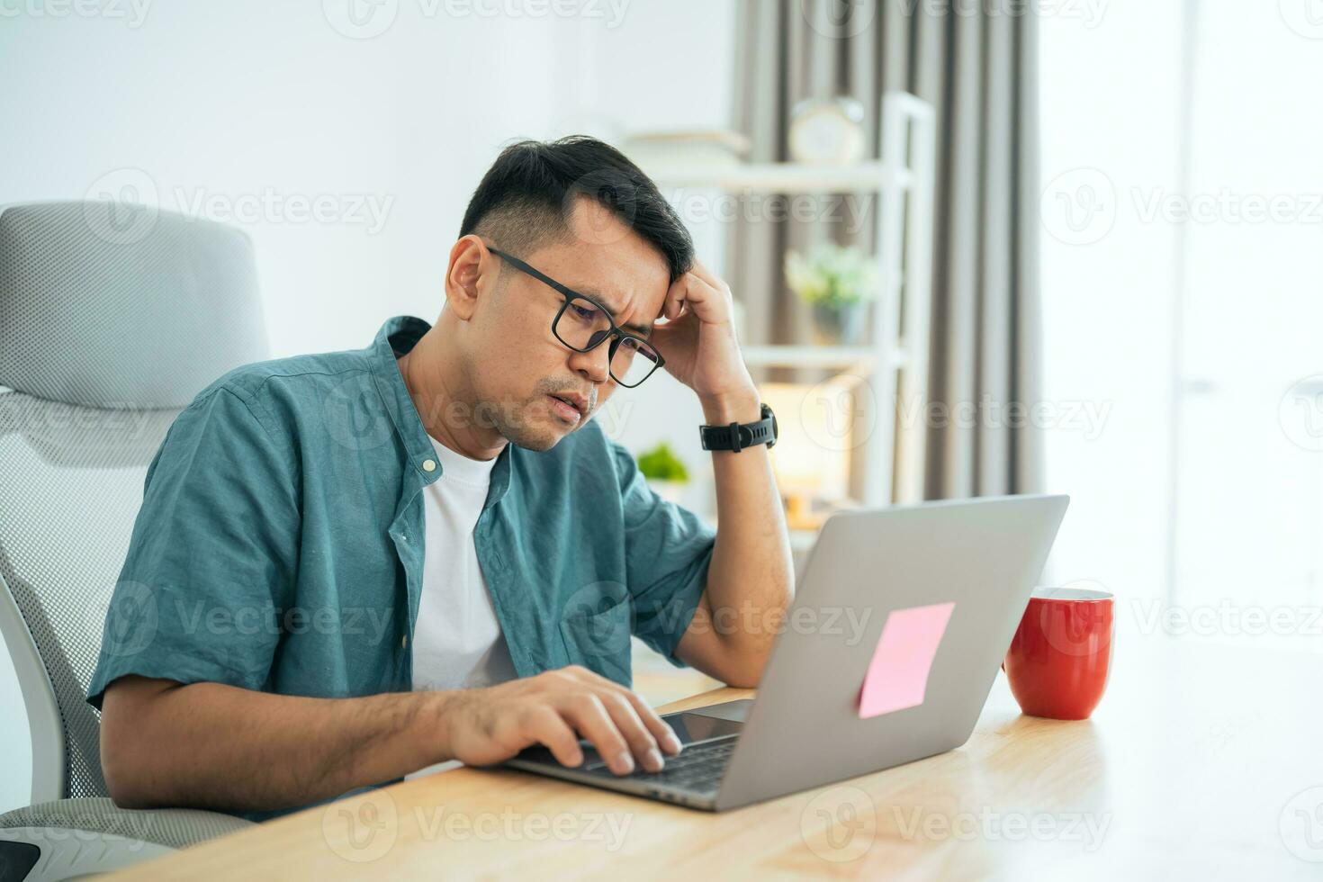 Asian Business man wear glasses and hand over head having stressful depression sad time while working on laptop at home. Depression man sad serios working from home. Working at anywhere concept. photo