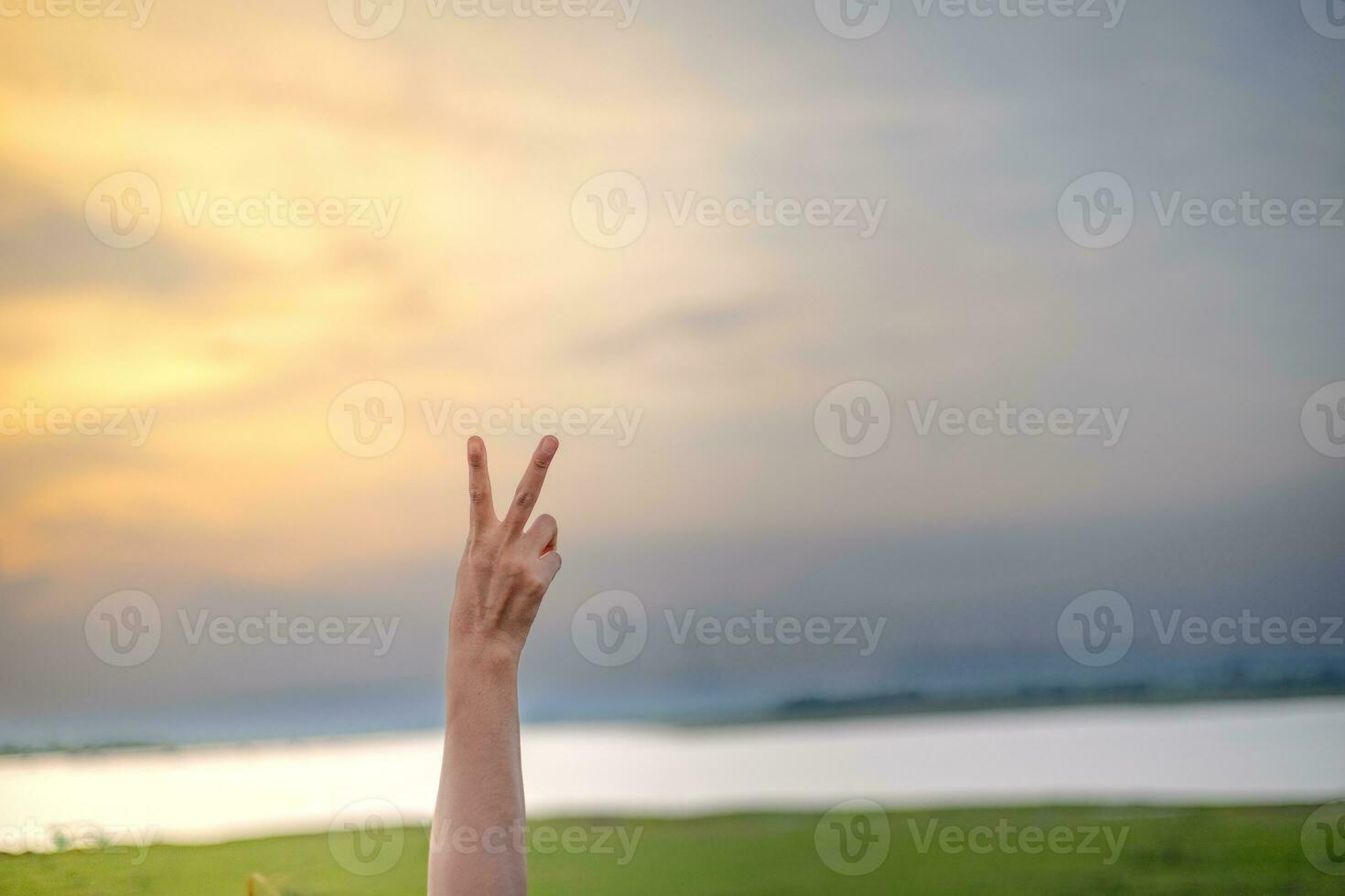 mujer mano levantamiento dos dedos a el cielo el suave noche luz de sol dijo yo a luchar. foto