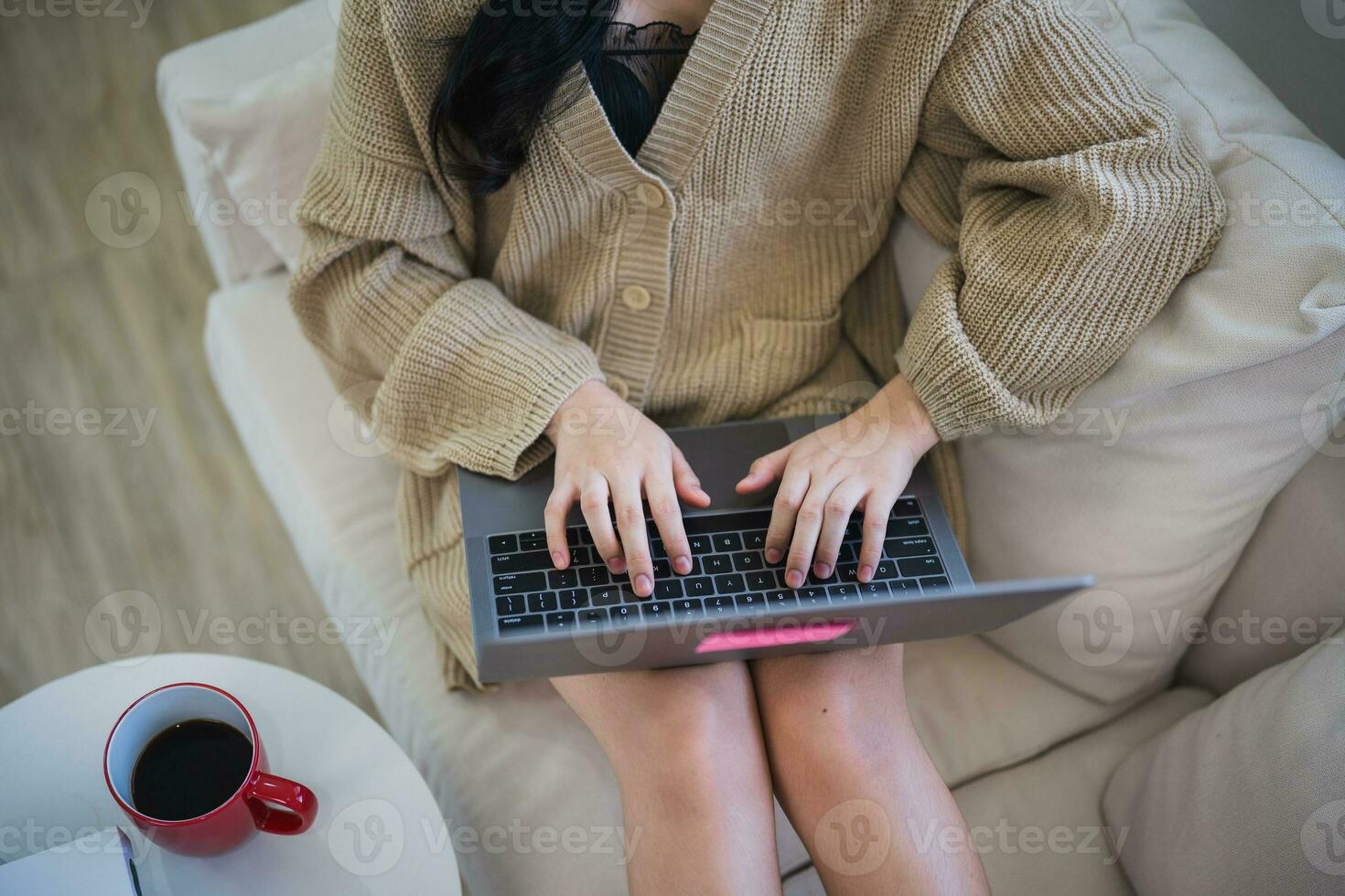 Top view. Asian freelance woman smile lying relax and typing on keyboard and working on laptop on sofa couch. Entrepreneur woman working for her business at living room home. Business work home. photo