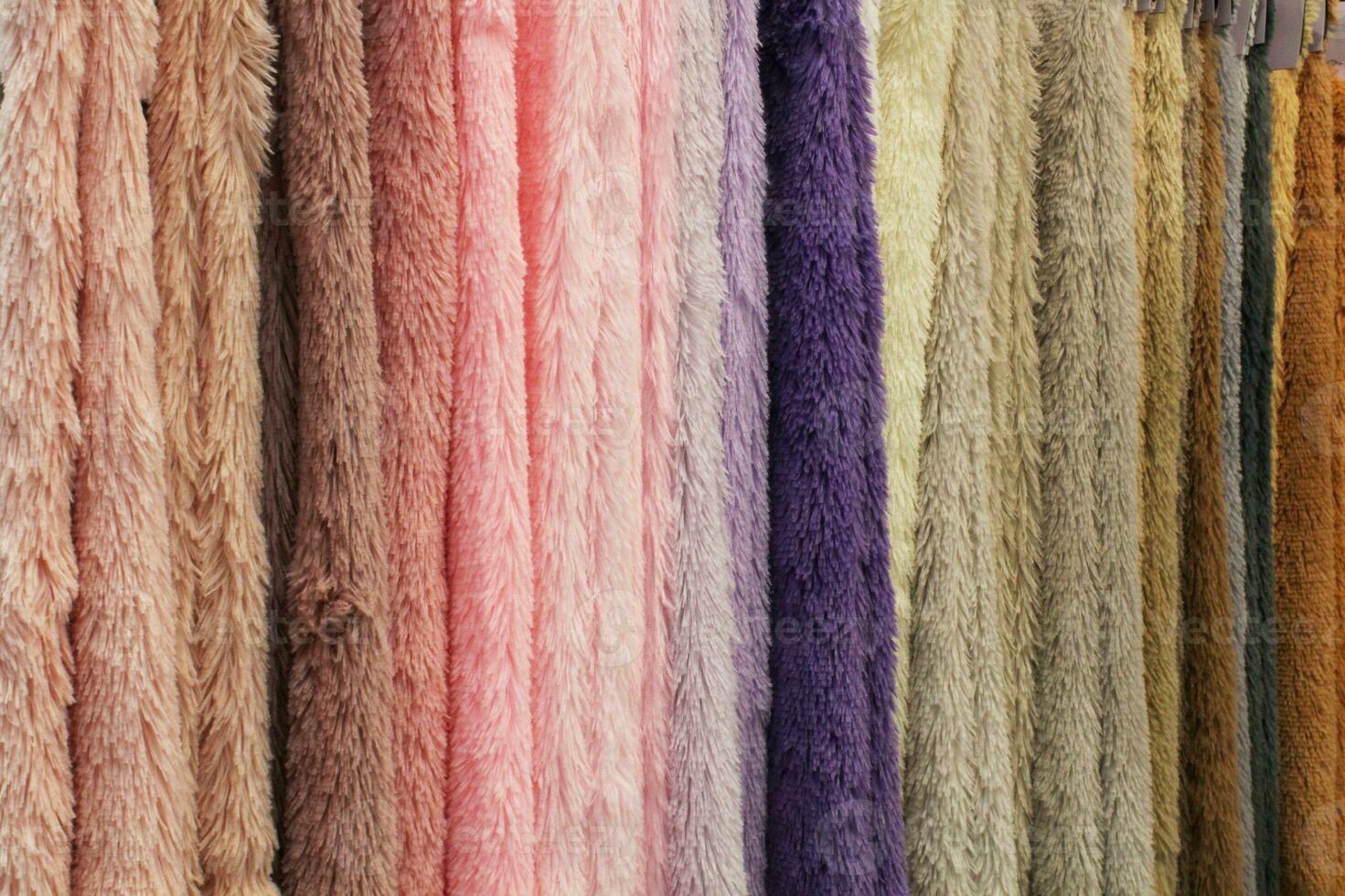 Colored textile plush samples of furniture and clothing upholstery of fabric in shop. Close-up palette of texture vertical stripes on hangers. Fashion industry concept. Sewing materials. Embroidering photo
