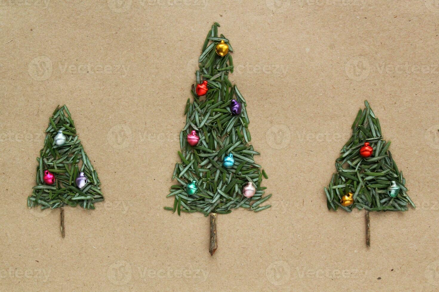 Green srpuce needles Christmas tree pattern with jingle bells on craft recycled paper. Ecological minimal design for holiday postcard. Eco friendly, zero waste, diy, nature concept. Flatlay, top view photo